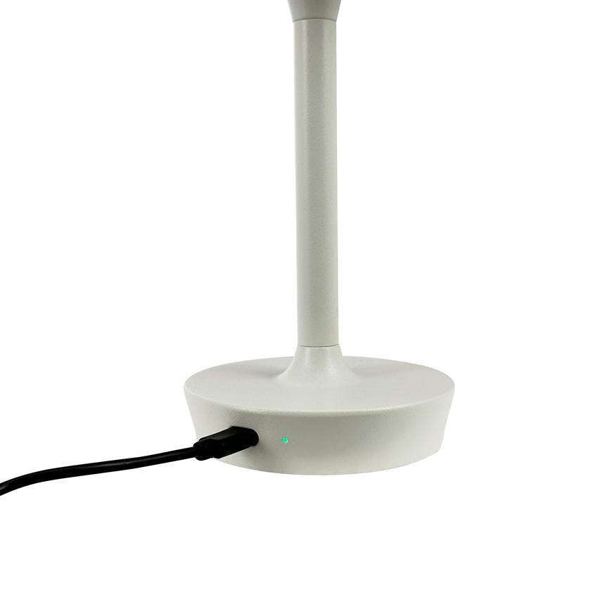 A white table lamp (foot and stem) is connected with a black cable; a small green LED lights up on the base, photographed close up against a white, uniform background.