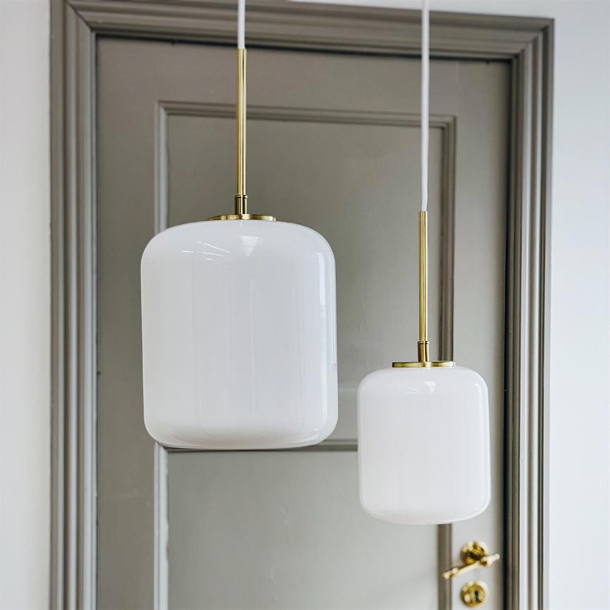 Two white, round glass pendants hang in brass suspensions in front of a classic gray door with inlays; the less pendant is slightly lower, and a shiny brass doorknob is seen to the right.