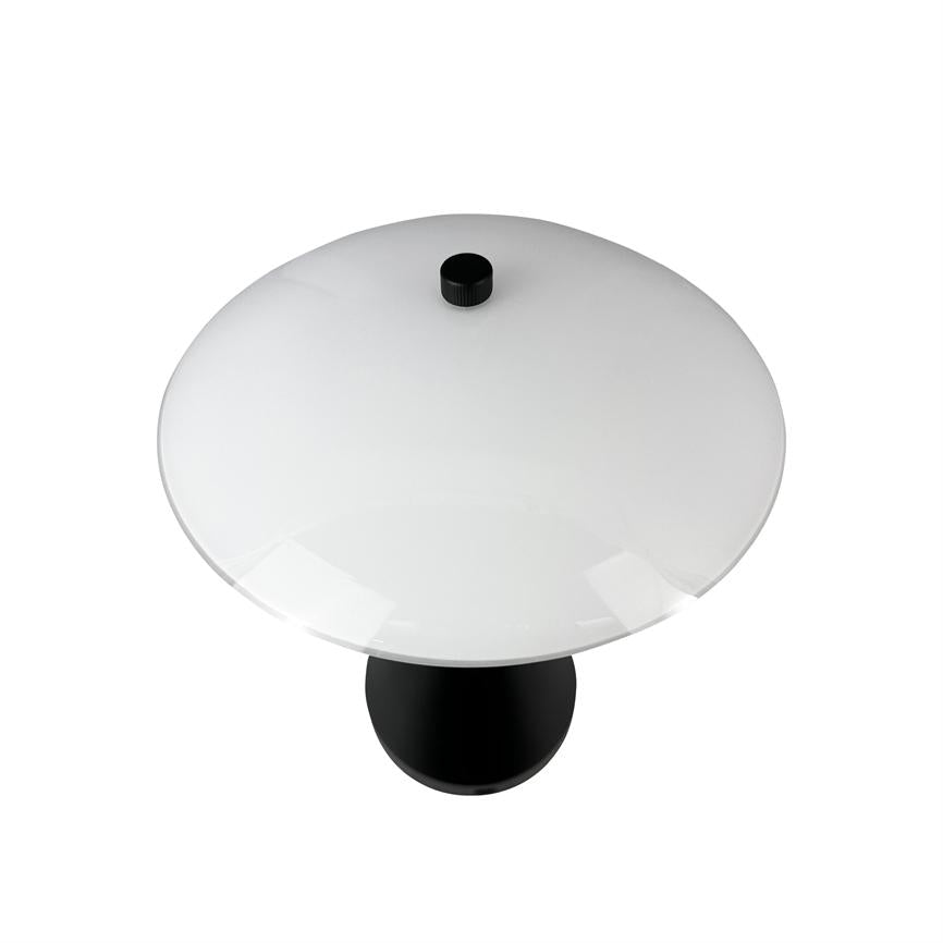 Table lamp stands alone on white background; it has a large round white dome with a black knob at the top and a black cylindrical foot, seen from above.