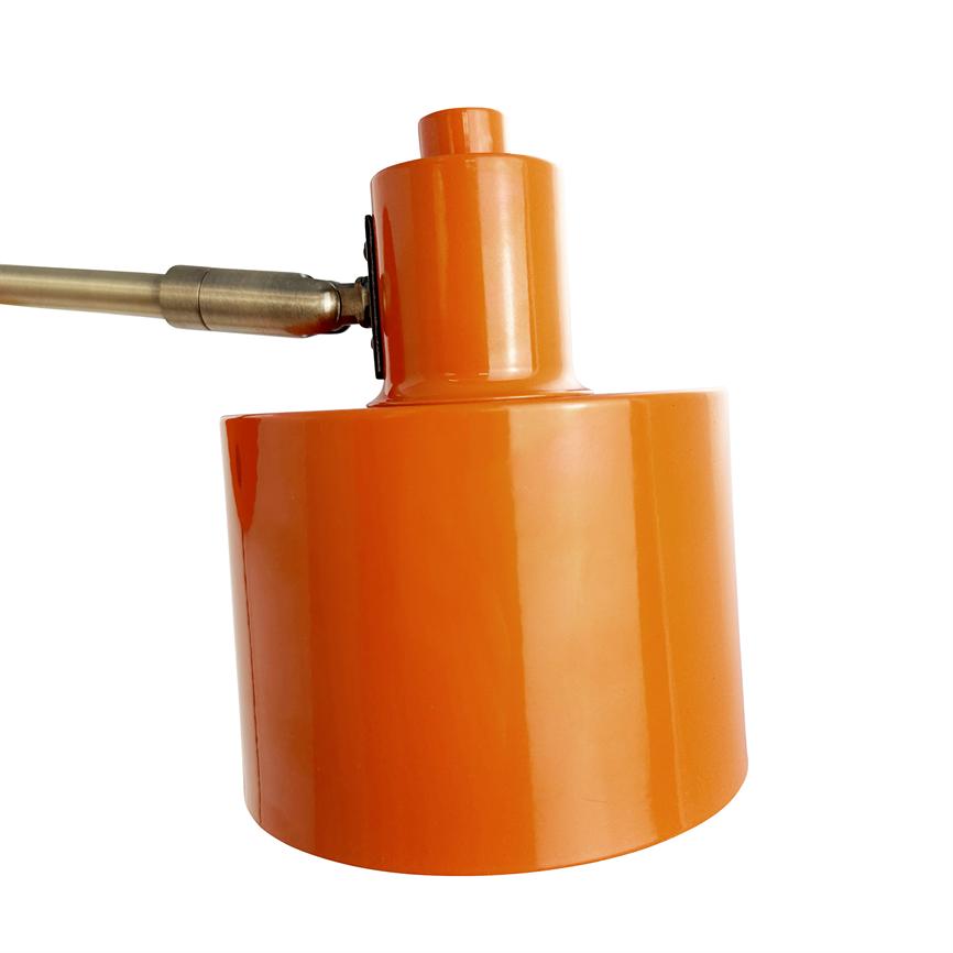 Orange cylindrical lamp head sits angled on a brass arm, with a reflective lacquer finish and highlighted against a clean, white background.