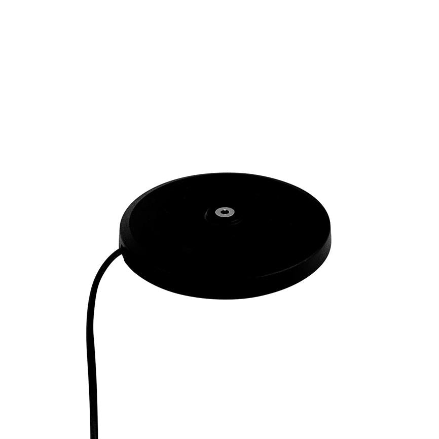 A round, black disk (puck) with a small metal ring in the middle; it has a black cable attached and stands alone against a uniform white background.