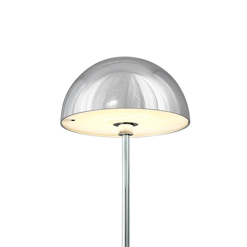 Chrome floor lamp emits soft, warm light under a hemispherical shade; slim metal bar and reflective chrome surface against uniform white background.