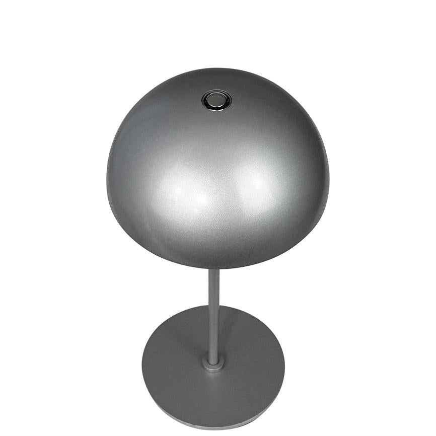 Sølv bordlampe står på en tynd søjle med rund fod; rund kuppelskærm med lille trykknap øverst; hvid, neutral baggrund.