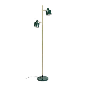 En gulvlampe med to justerbare grønne skærme, der peger i forskellige retninger, på en slank messingstang og rund grøn fod; kabel ligger løst mod hvid baggrund.