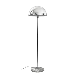 A chrome floor lamp with hemispherical shade stands on a slim rod and round marble base; black wire lies loosely on white background in an empty bright environment.