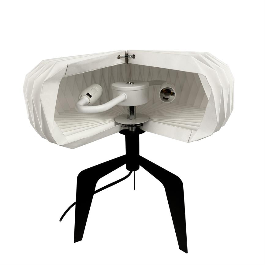 White, folded lampshade cut open, showing two lamp holders, central fixture and cord; mounted on black tripod with flat folded interior pattern and neutral white background.