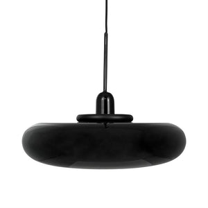 A black, donut-shaped pendant lamp hangs from a thin wire against a uniform white background with a glossy, reflective glass surface.