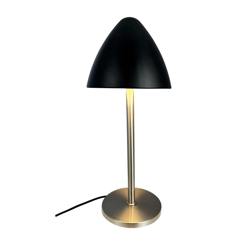 Table lamp casts warm light downwards; slim brushed metal bar and round base stand on white background, with black dome and visible black cord.