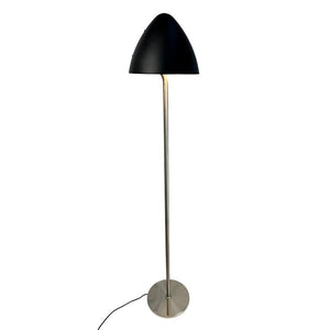 Standing floor lamp with black dome-shaped shade, thin chrome rod and round metal base; a black cord extends from the foot against a uniform white background.
