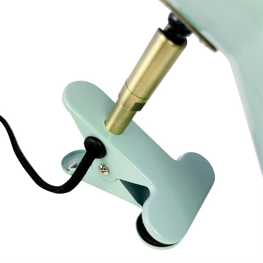 Mint green metal clamp holds a black cloth covered wire, connected to a brass rod on a lamp; close up shot with neutral white background.