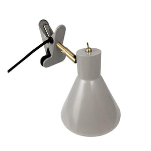 Clamp lamp with gray conical shade; golden joint detail connects shield to gray clamp, black wire leads away; neutral white background.