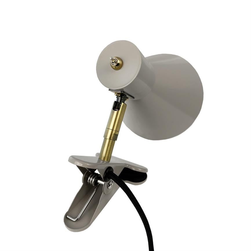 Clip-on lamp with gray shade, adjustable gold-colored rod and black textile cord; the lamp is angled and clamped on a metal clip against a white, neutral background.