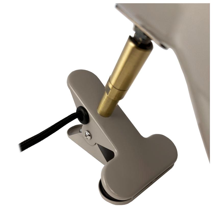 Beige metal clip, open, holds a black textile covered cable to a brass colored lamp fitting on a lamp arm, photographed against a white background.