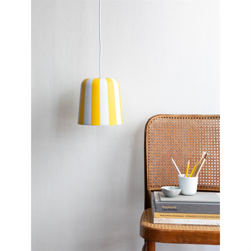 Yellow-white striped pendant lamp hangs above a rattan chair with pile of books, mug with pencils and a small bowl, in front of a white wall.
 
 Text: "Wonderwall Case Studies"; "BUILDING CULTURE AND CONSERVATION VALUES"