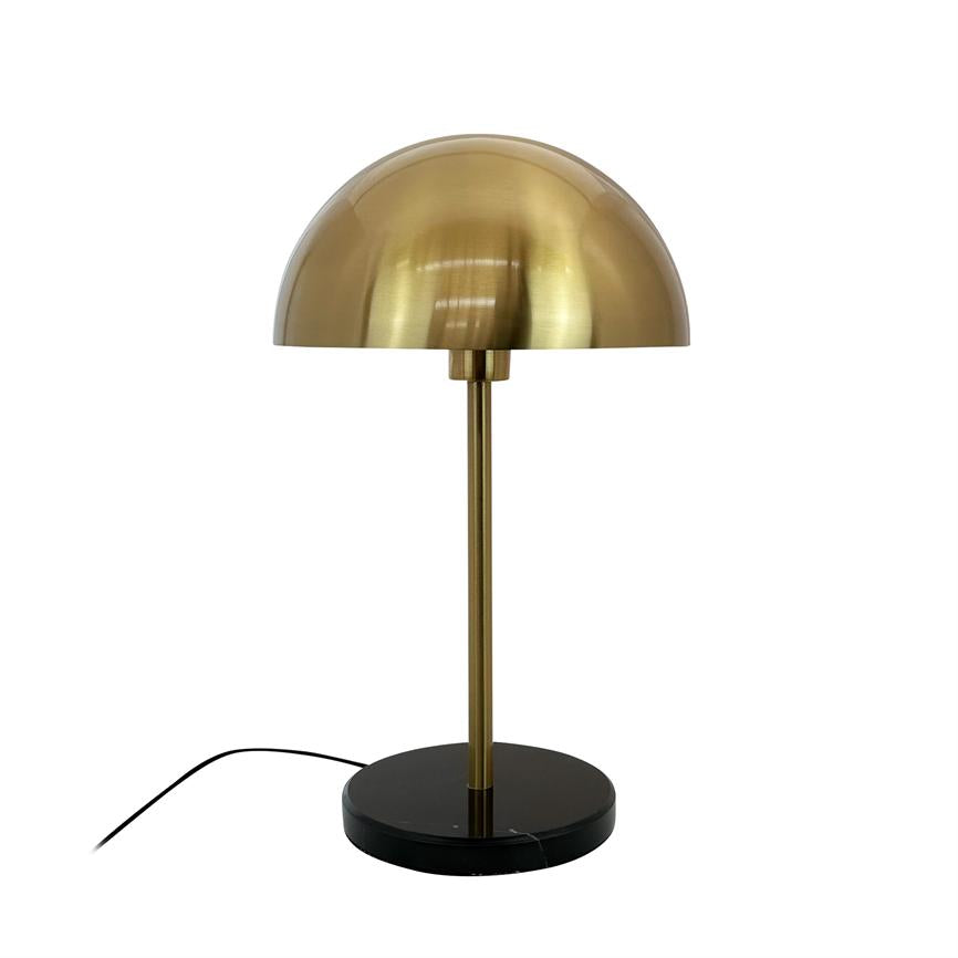 Table lamp with hemispherical, brushed brass shade; slender brass rod; stands on black, round marble base with visible black cord against white background.