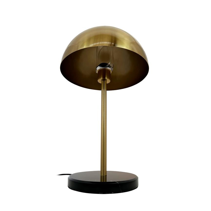 Table lamp with domed brass shade, standing on a slim brass column and round black marble base; placed against a uniform white background.