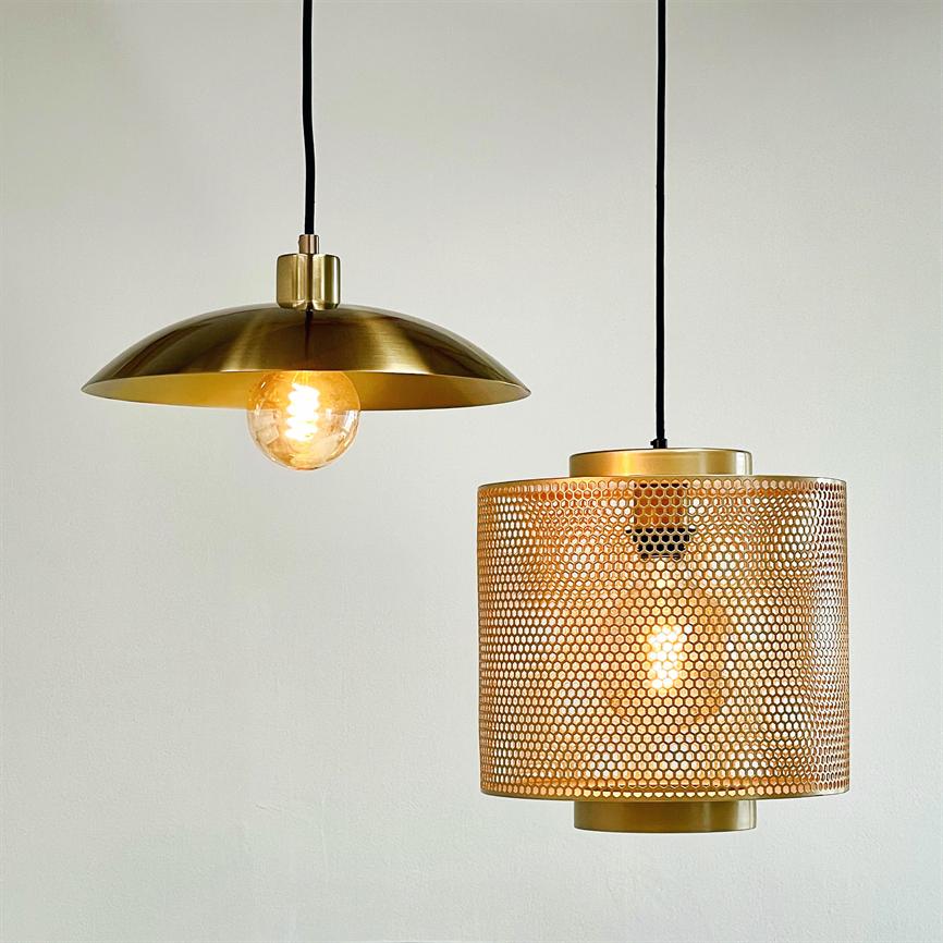 Two hanging lamps: a disc-shaped lamp with visible incandescent bulb and a cylindrical lamp with a perforated metal shade; both are lit, casting warm, golden light against a white wall.
