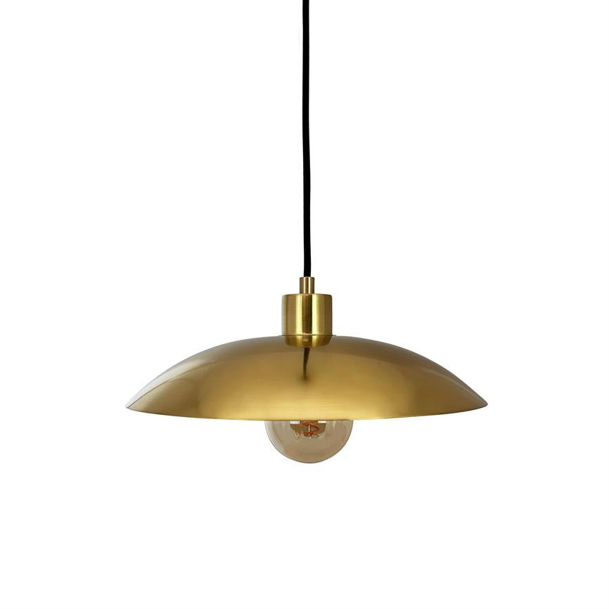 A brass colored one pendant hanging from a black cord, shields and encloses a visible incandescent bulb under a low, round shade against a uniform white background.