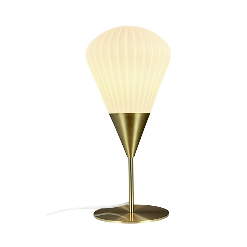 Bordlampe – lyser med varmt, blødt lys; cremefarvet ribbet kuppelskærm ovenpå en konisk, børstet messingholder, slank messingstang og rund messingfod; hvid ledning på hvid baggrund.
