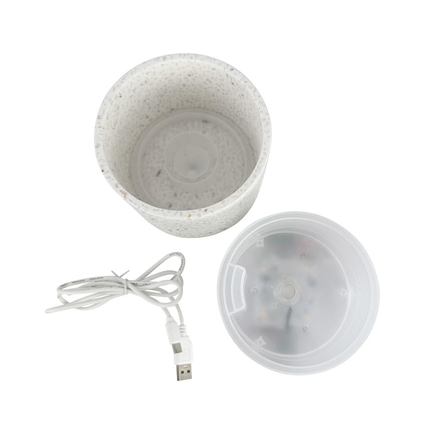 White, variegated cylindrical container; it is separated into three parts with a transparent plastic lid and a rolled-up USB cable; the parts lie on a white background.