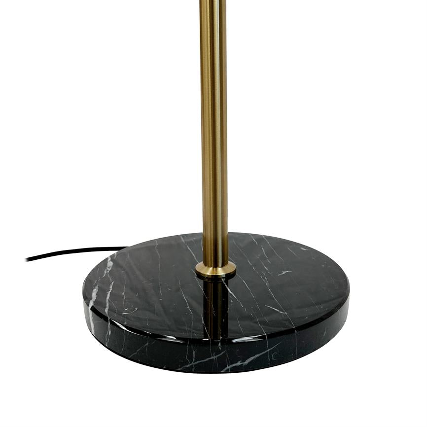 Black, round marble base supports a vertical, slender brass rod; a black cable lies partially visible on a white background, close-up shows shine and white veins in the marble.
