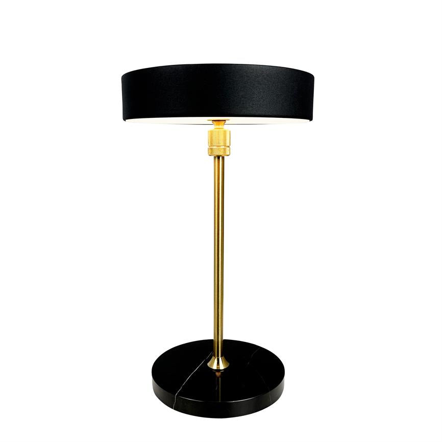Table lamp with black cylindrical shade, slim gold colored rod and round black marble base; standing upright on a white background, functional and elegant.