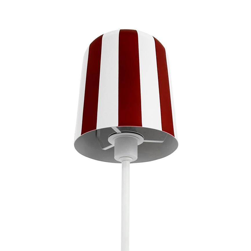 Lamp hangs from a thin, white cord; cylindrical screen with red and white vertical stripes; simple white studio background.