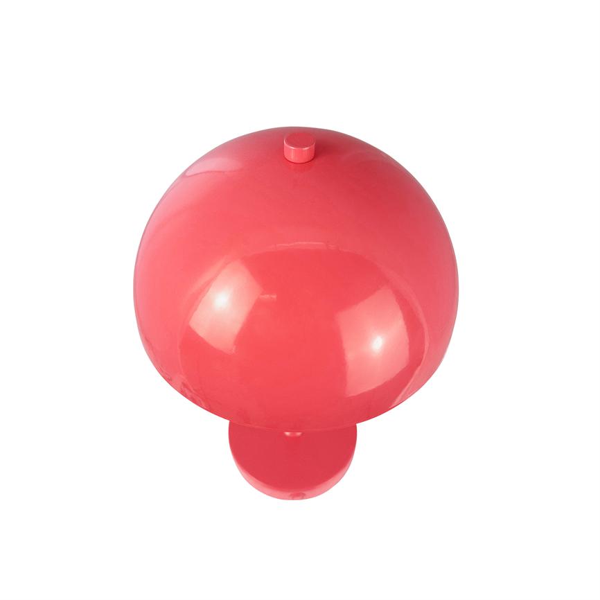 Red mushroom-shaped plastic object, resting on a uniform white background, viewed from above; glossy, reflective surface with a small round knob on top.