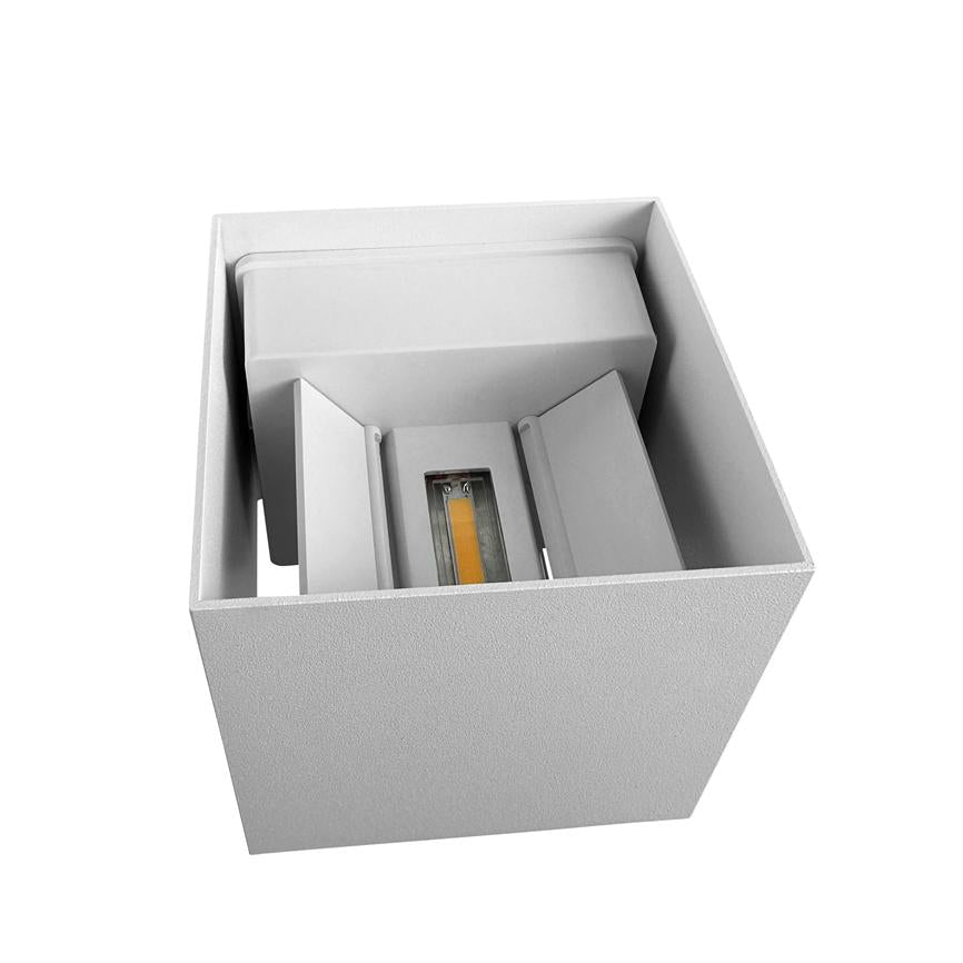 A white, square lamp unit houses a central yellow LED module; internal shields guide the light and an open top displays a textured case against a neutral white background.