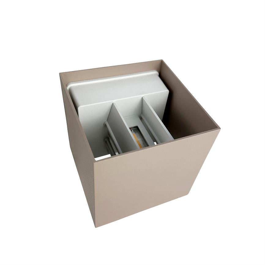 Square beige wall lamp houses a white internal LED module with three vertical partitions; the lamp is seen obliquely from above against a uniform white background.