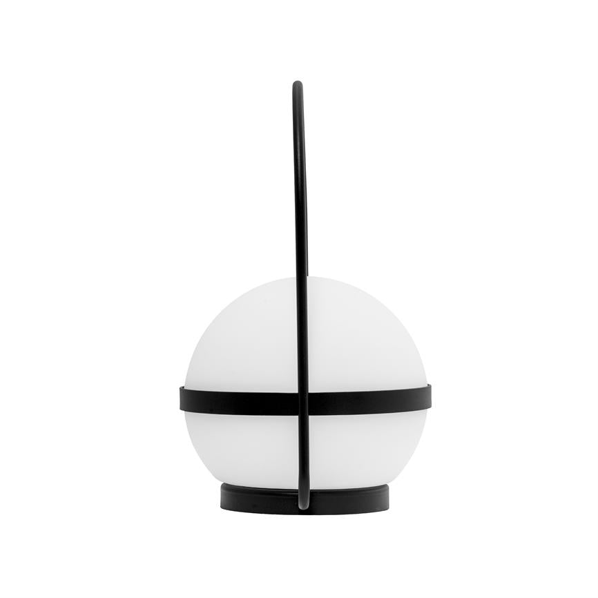 A spherical table lamp stands on a round black base; a white opal glass is surrounded by a black metal ring and a vertical black handle, against a uniform white background.