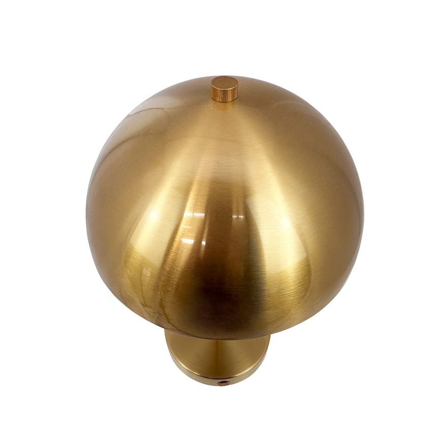 Spherical brass lamp with a brushed, reflective surface rests on a short cylindrical base in front of a plain white background.