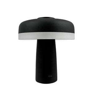 Table lamp stands with wide, round shade and cylindrical base; the bottom edge of the screen is white, the rest black, against a uniform white background.