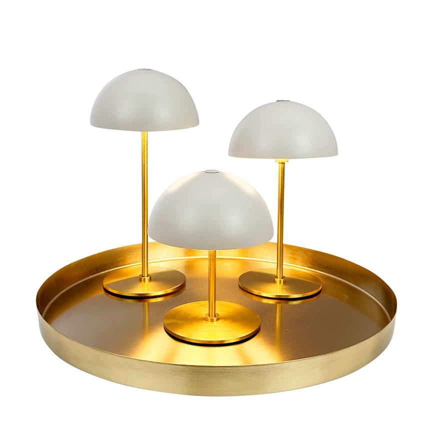 Three small white dome lamps stand on a round gold-coloured tray; they emit warm light which forms soft reflections on the hill against a white background.