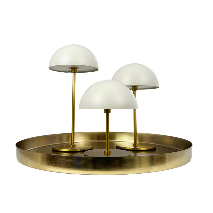 Three white dome lamps stand on slender brass shafts, mounted in a round, polished brass tray, set against a white, neutral background.