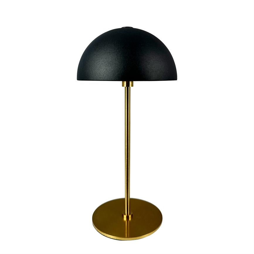 Table lamp with black hemispherical shade, thin brass colored rod and round brass base; stands centered against a uniform white background.