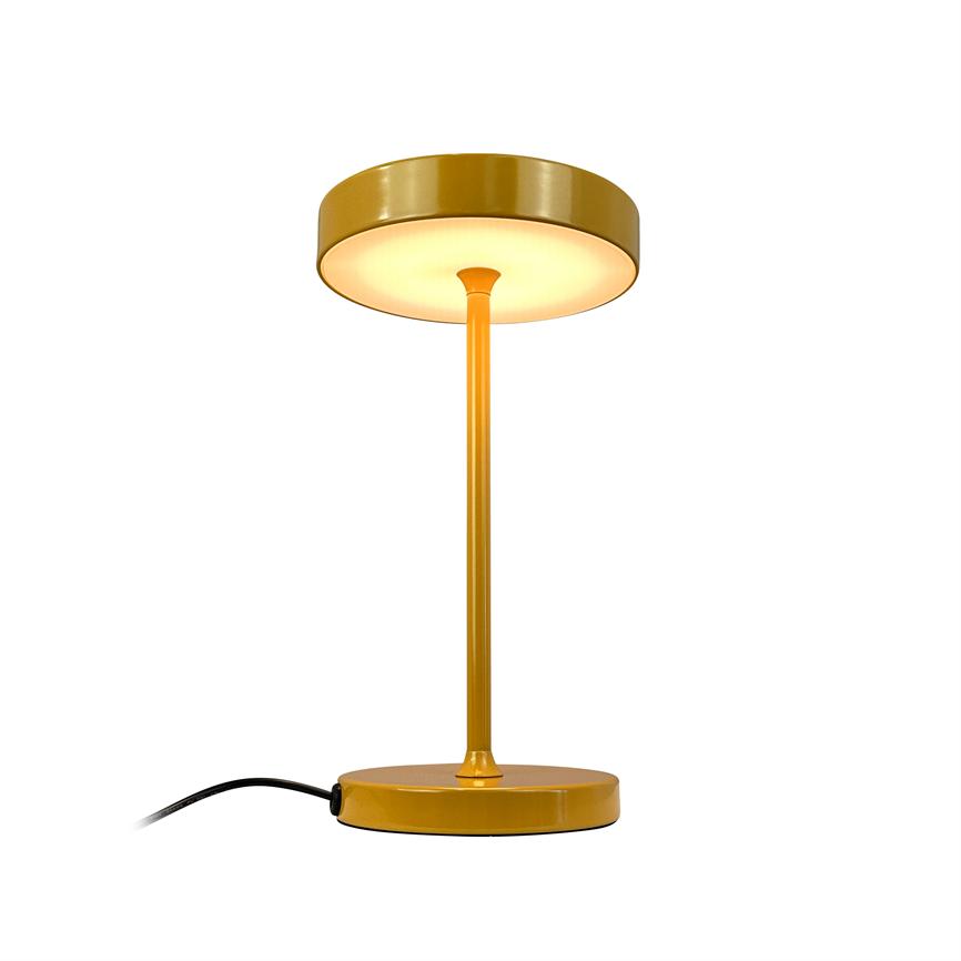 A yellow table lamp with a disc-shaped shade emits warm downward light, standing on a round base with a slim rod and visible black cord against a white background.