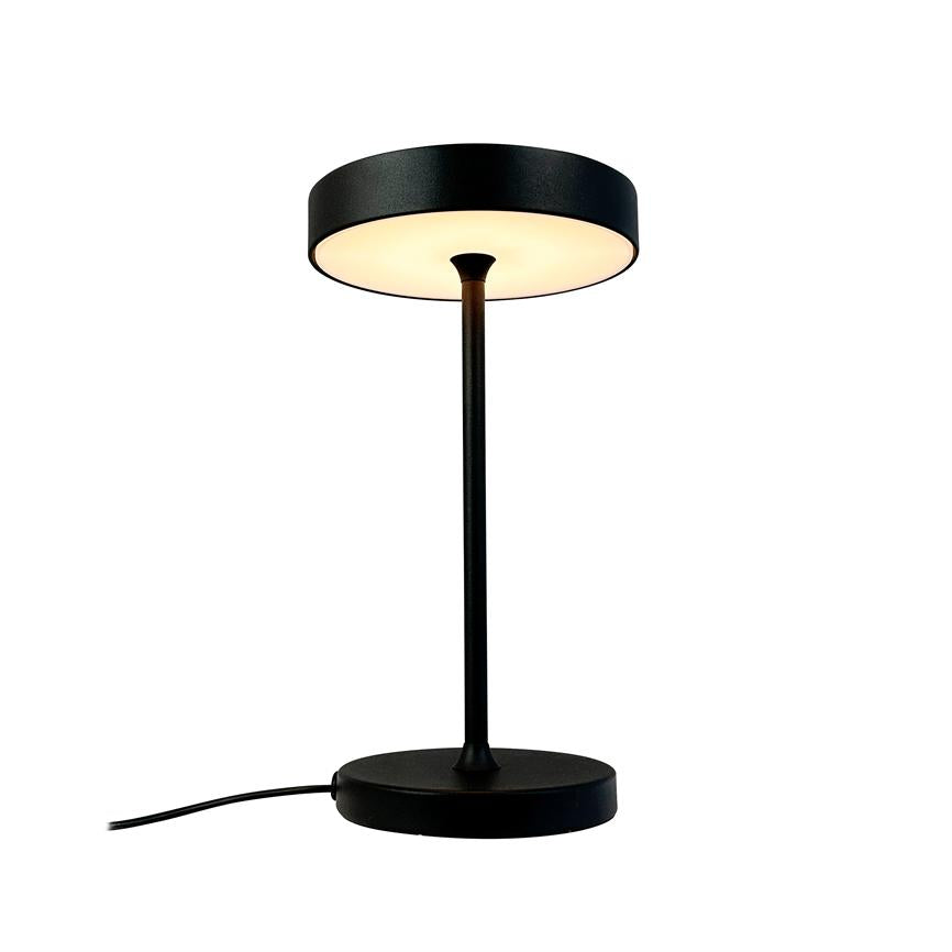 Black, modern table lamp with round shade and slim base, warm downwards; stands centered on white background with visible power cable, minimalistic product photo.