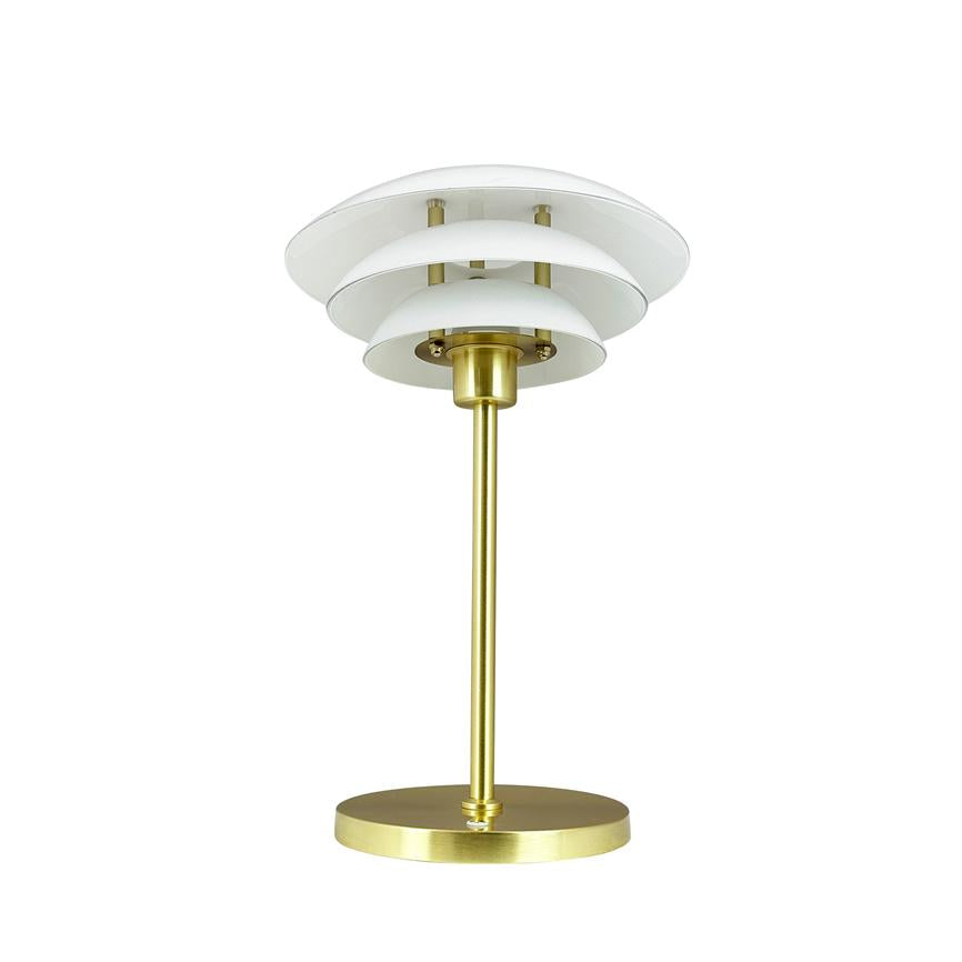 A table lamp in brushed brass stands on a round base, has a slim rod and three layered white shades; placed in front of a neutral white studio background.