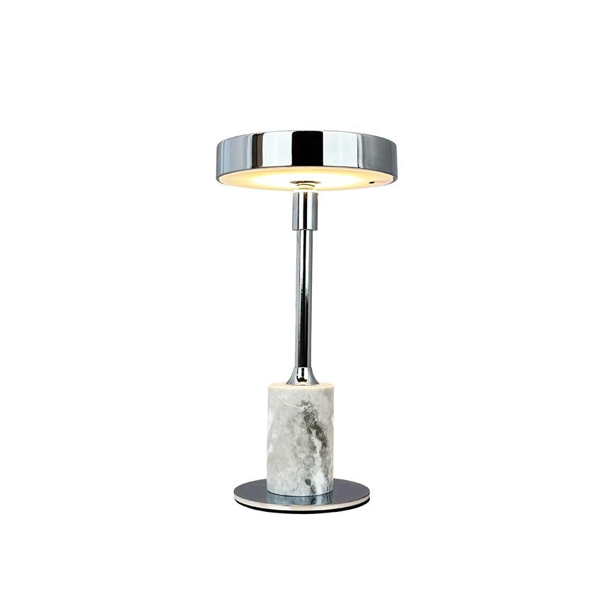 Table lamp emits warm, diffuse downward light; slim chrome rod and round chrome shade rests on cylindrical marble base on white background.