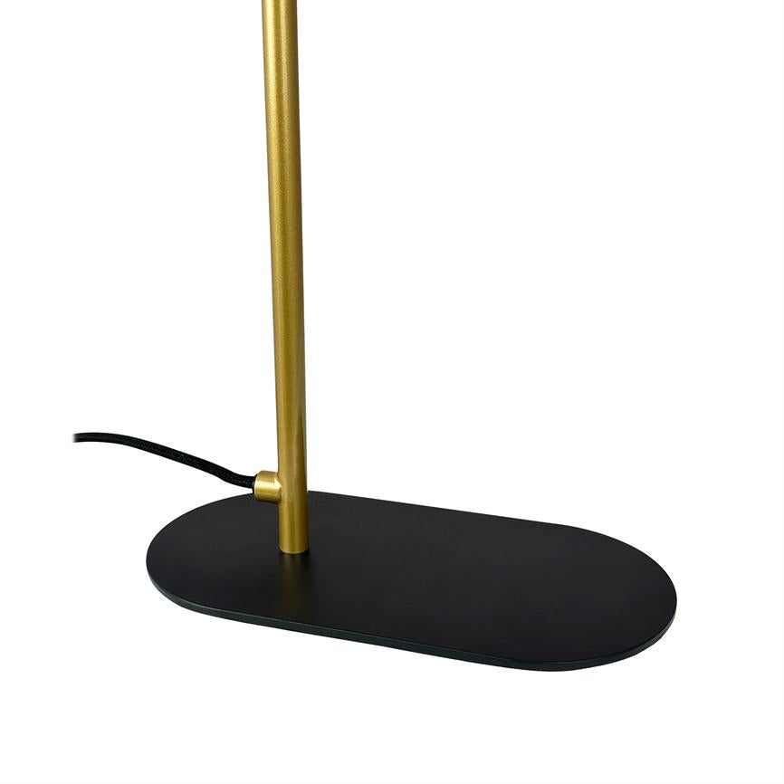 Golden lampstand stands in oval black base; black fabric cord runs out from the side. Minimalist table lamp on a uniform white background.