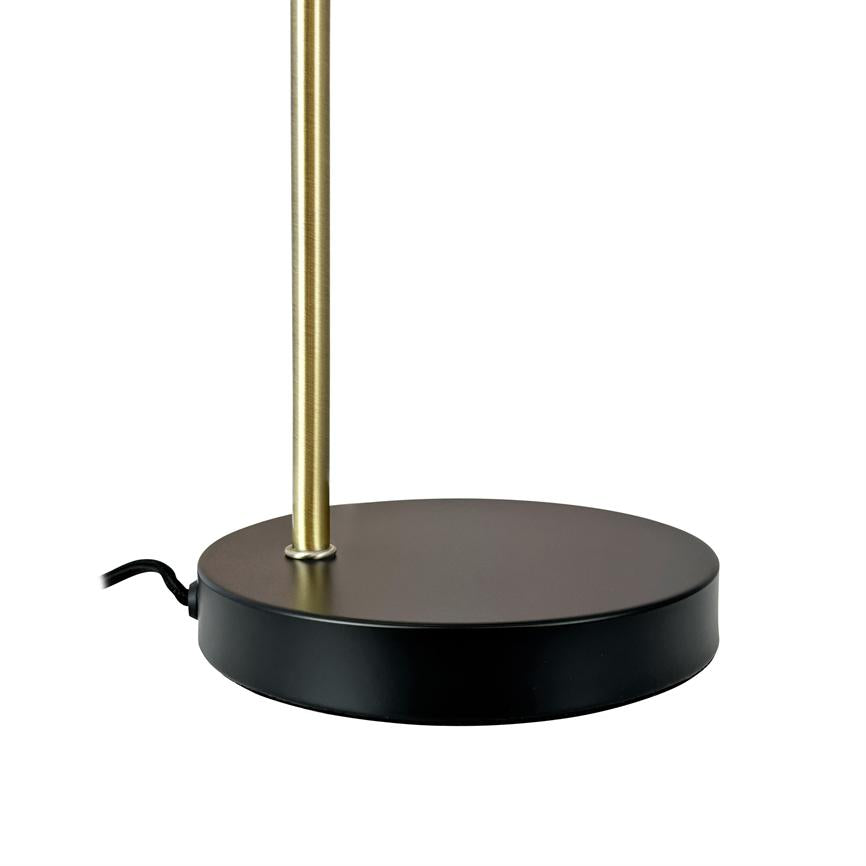 The lamp's round black base supports a vertical, thin brass rod; a black power cord sticks out to the left on a white background.