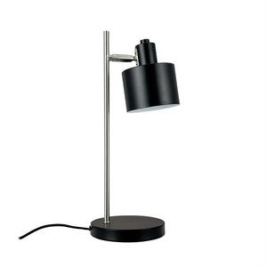 Desk lamp with black cylindrical shade, tilting head, mounted on a slender silver rod and round black base; black wire lies to the side on a white background.