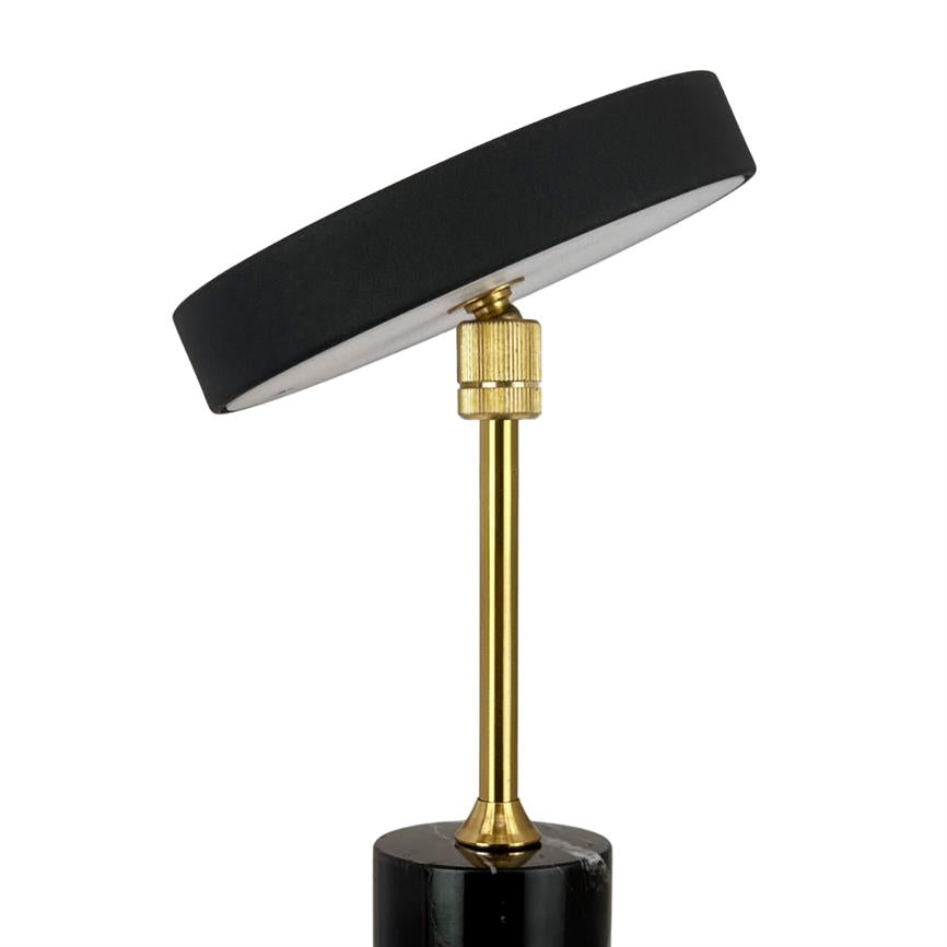 Table lamp with a tilted, flat black shade, mounted on a slender brass column with adjustable coupling, sitting on a round black marble base.