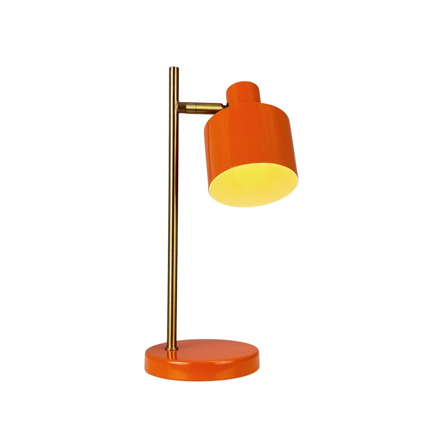 An orange table lamp shines downwards; the screen is cylindrical and tilted on a vertical brass rod that stands on a round orange base against a uniform white background.