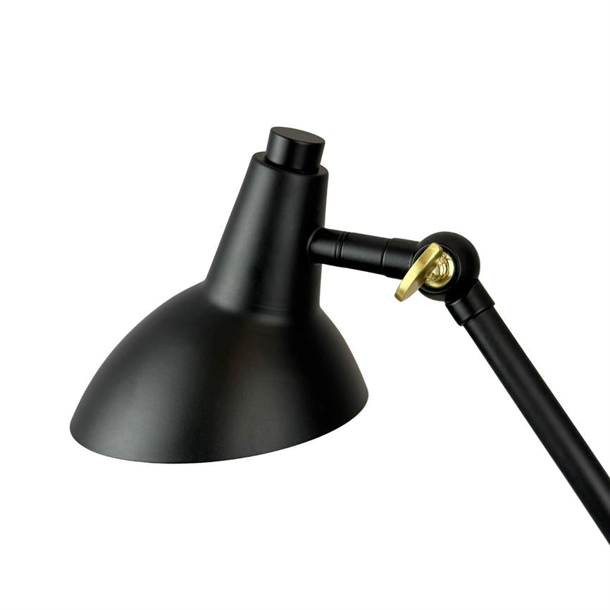 Black metal desk lamp directs the light downwards; adjustable joint and swivel joint secured with a golden screw; isolated on white background without surroundings.