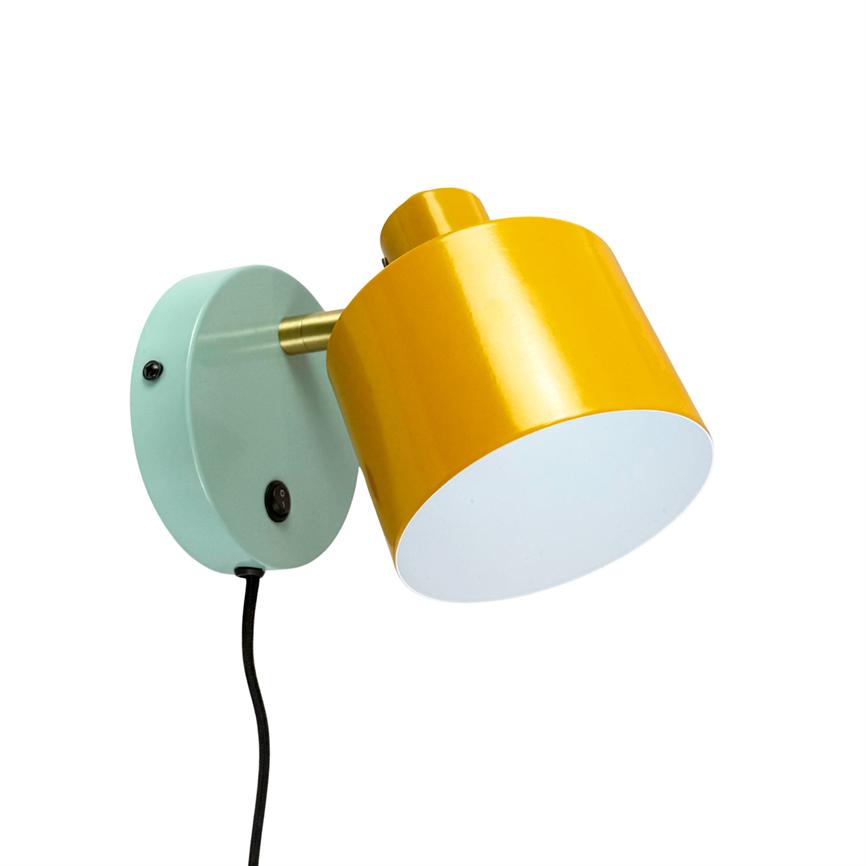 Wall lamp points obliquely downwards; yellow cylindrical shade mounted on mint green round wall bracket with brass rod; black fabric cord hangs vertically.