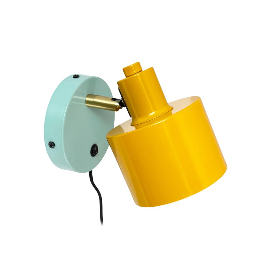 Wall lamp points obliquely; yellow cylindrical lampshade mounted on a mint green wall bracket with brass joints and black cord against a white background.