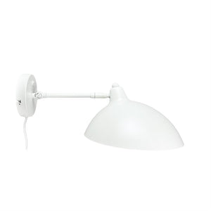 Wall lamp mounted on round wall bracket, arm extended, large white dome shade angled downwards; white wire hangs freely against a uniform white background.