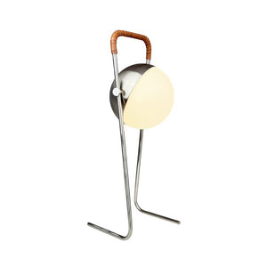 Table lamp with round, partially covered opal glass dome (lit), mounted on two slender chrome rods with angled feet and leather-wrapped bracket over top; displayed on a white background.